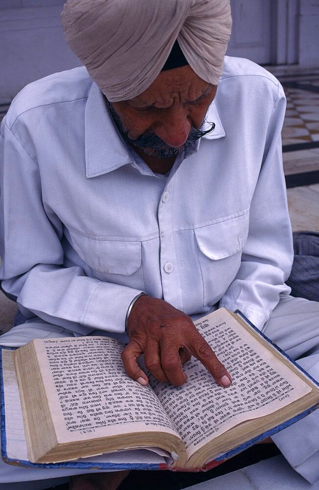 Man reading Sikh holy book at the Golden Temple, Amritsar, Punjab, India