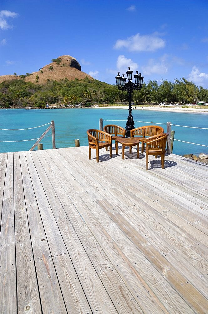 Signal Hill on Pigeon Island National Historic Park seen from a nearby wooden jetty with a table and chairs beside a wrought iron lamppost, Gros Islet, St Lucia