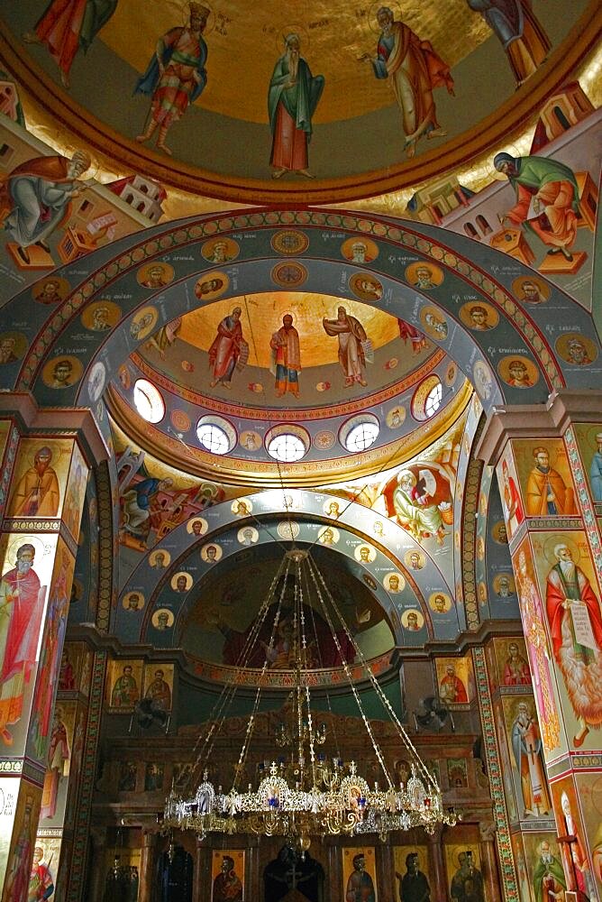 Nazareth, Interior of the Greek Orthodox Church of St, Gabriel also known as the Church of the Annunciation located over the spring that fed Marys Well, Interior domed ceilings and archways decorated with paintings of biblical scenes and the saints wall hangings and tiled mosaics, Ornate candelabra hanging from centre framed by arch, Sea of Galilee, Hazafon, Israel