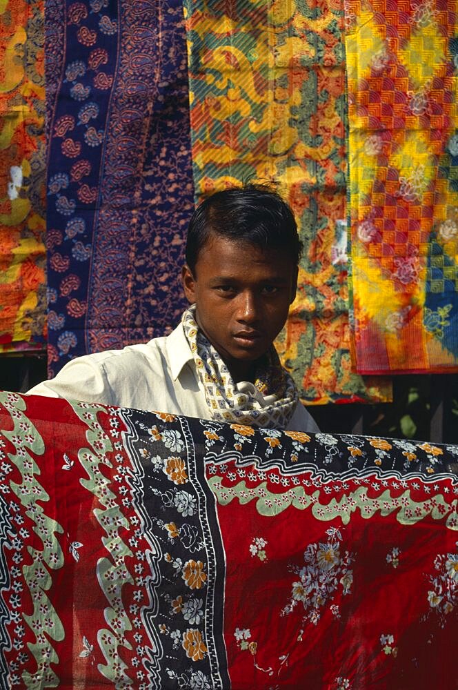 Fabric trader holding up printed cotton, Asia