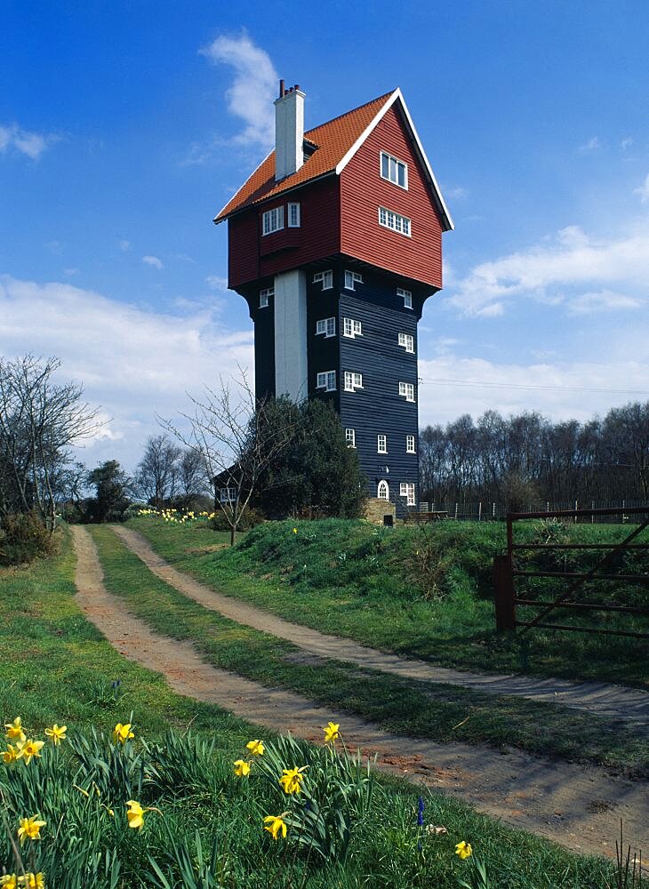 England, Suffolk, Thorpeness, Converted former water tower the House in the Clouds with daffodils growing beside footpath in the foreground