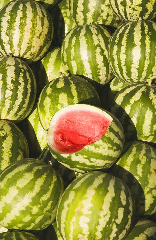 Turkey, Aydin Province, Kusadasi, Fresh watermelon on sale at town produce market with fruit at centre cut open to reveal red flesh and seeds