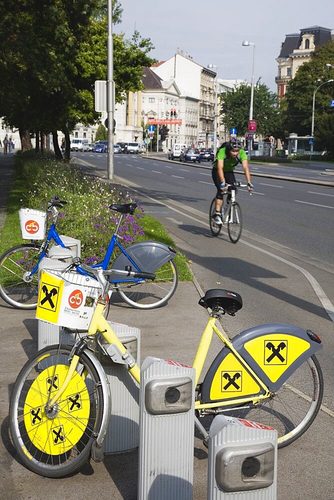 Austria, Vienna, Neubau District, Bicycles for use in city centre with approaching cyclist on road behind