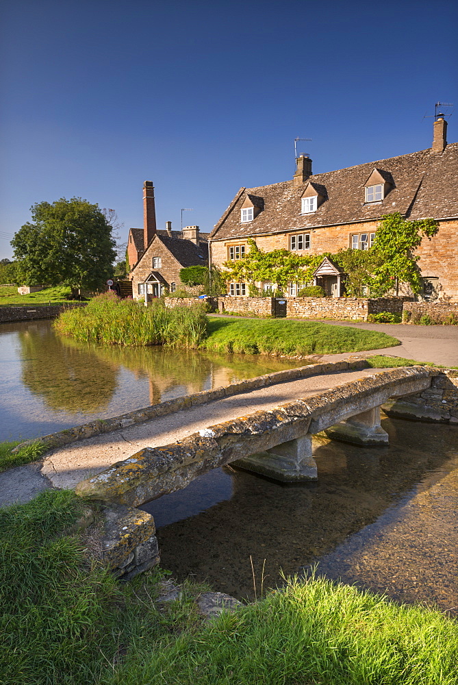 Stone footbridge and cottages in the picturesque Cotswolds village of Lower Slaughter, Gloucestershire, England, United Kingdom, Europe