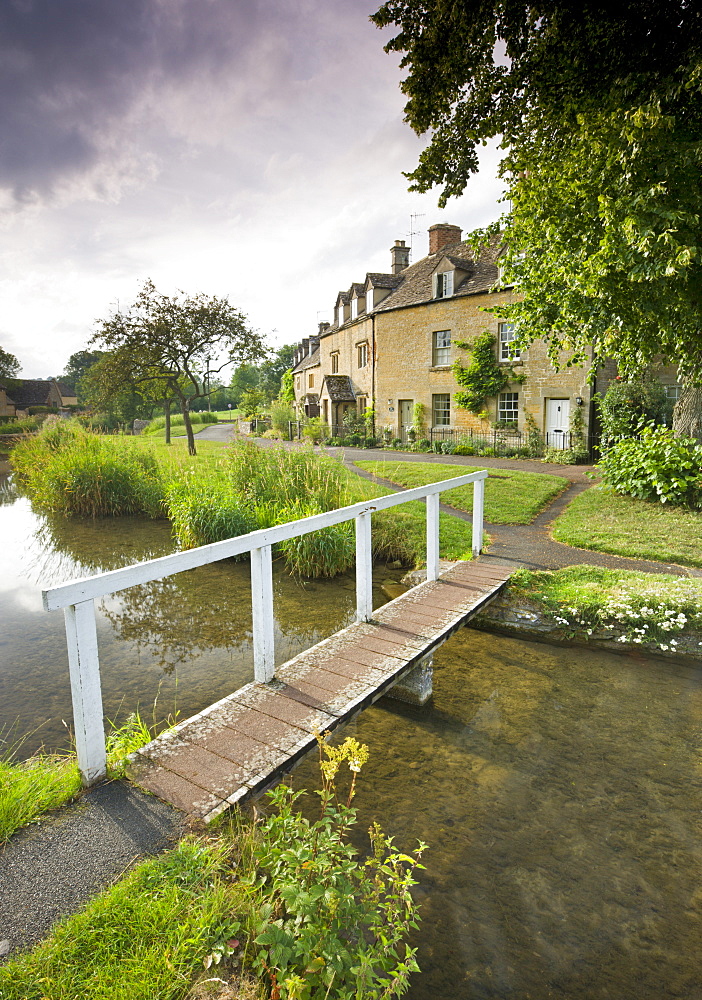 Cottages and footbridge over the River Eye in the Cotswolds village of Lower Slaughter, Gloucestershire, England, United Kingdom, Europe 