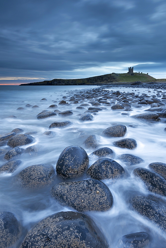 Dunstanburgh Castle at dawn from Embleton Bay, Northumberland, England, United Kingdom, Europe 