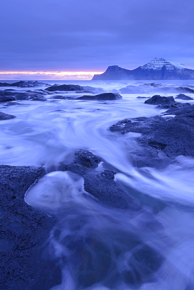 Surging waves rush over the basalt ledges of Gjogv at dawn, Eysturoy, Faroe Islands, Denmark, Europe