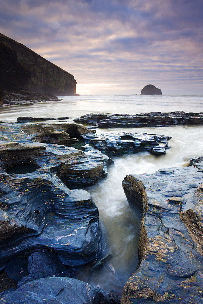 Eroded slate rocks on the beach at Trebarwith Strand, looking towards Gull Rock, Cornwall, England, United Kingdom, Europe