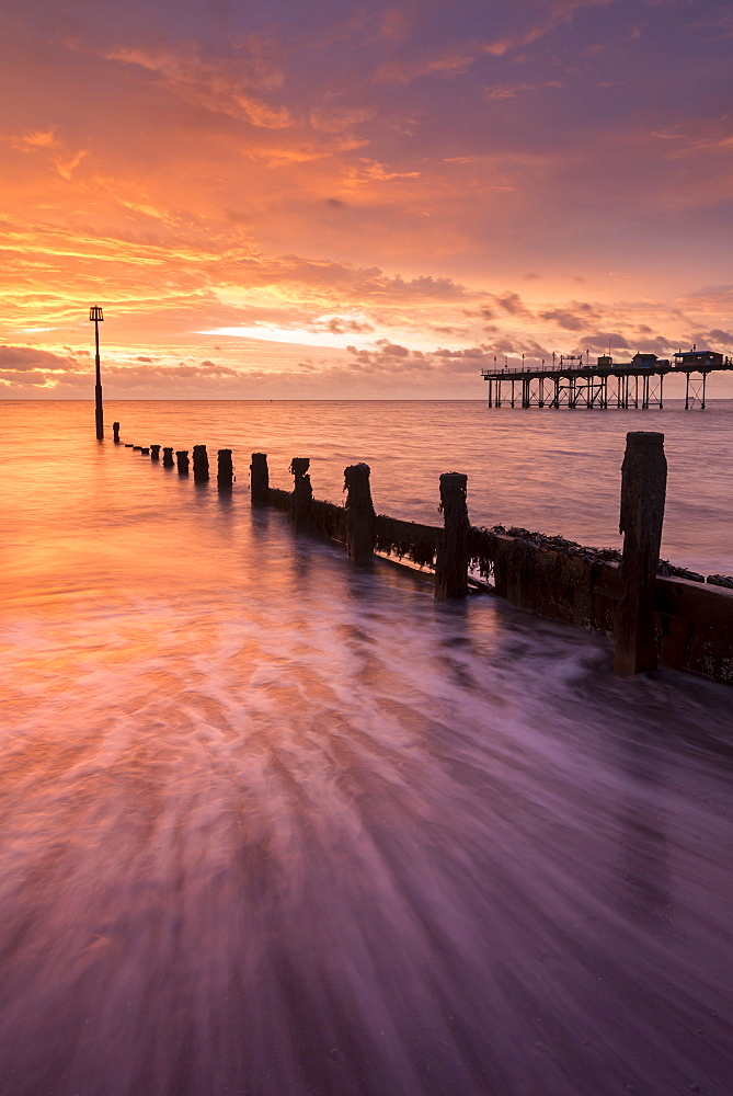 Beautiful colourful sunrise above the wooden groynes and pier at Teignmouth in Devon, England, United Kingdom, Europe