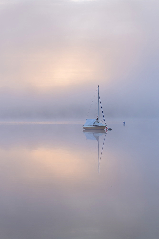 Sailing boat in misty conditions at dawn on Wimbleball Lake, Exmoor National Park, Somerset, England, United Kingdom, Europe