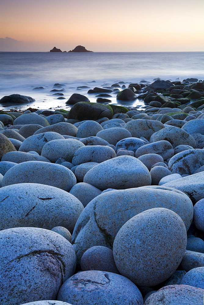 Circular boulders at Porth Nanven beach, with The Brisons island on the horizon, Cornwall, England, United Kingdom, Europe