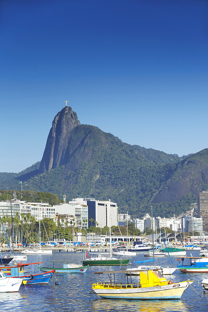 Boats moored in harbour with Christ the Redeemer statue in background, Urca, Rio de Janeiro, Brazil, South America 