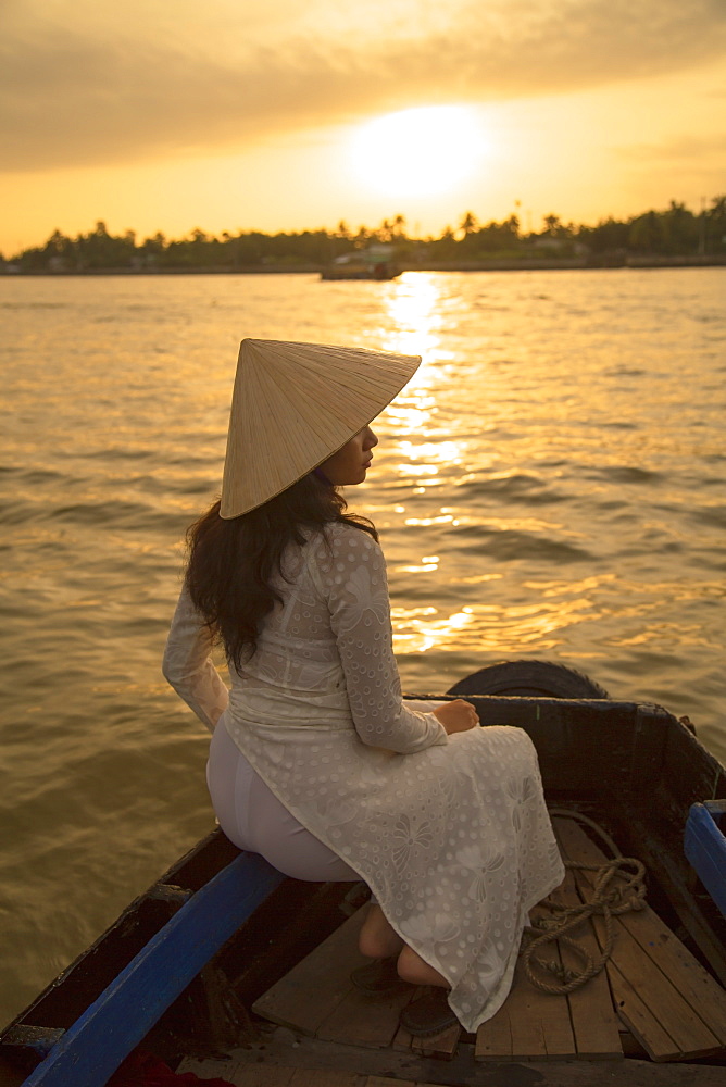 Woman wearing ao dai dress in boat at dawn, Can Tho, Mekong Delta, Vietnam, Indochina, Southeast Asia, Asia