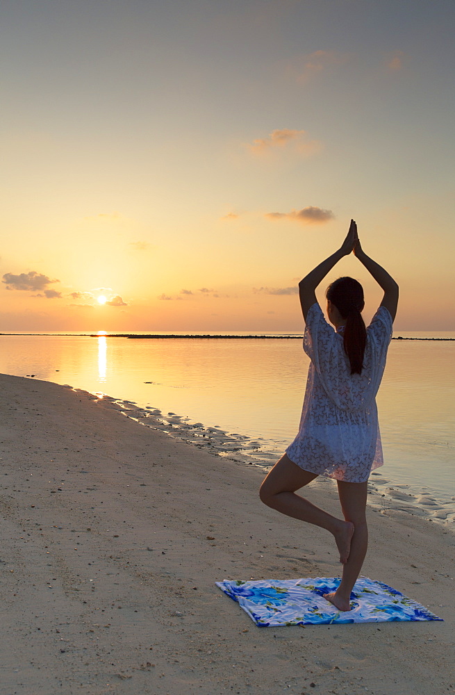 Woman practising yoga at sunrise, Rasdhoo Island, Northern Ari Atoll, Maldives, Indian Ocean, Asia