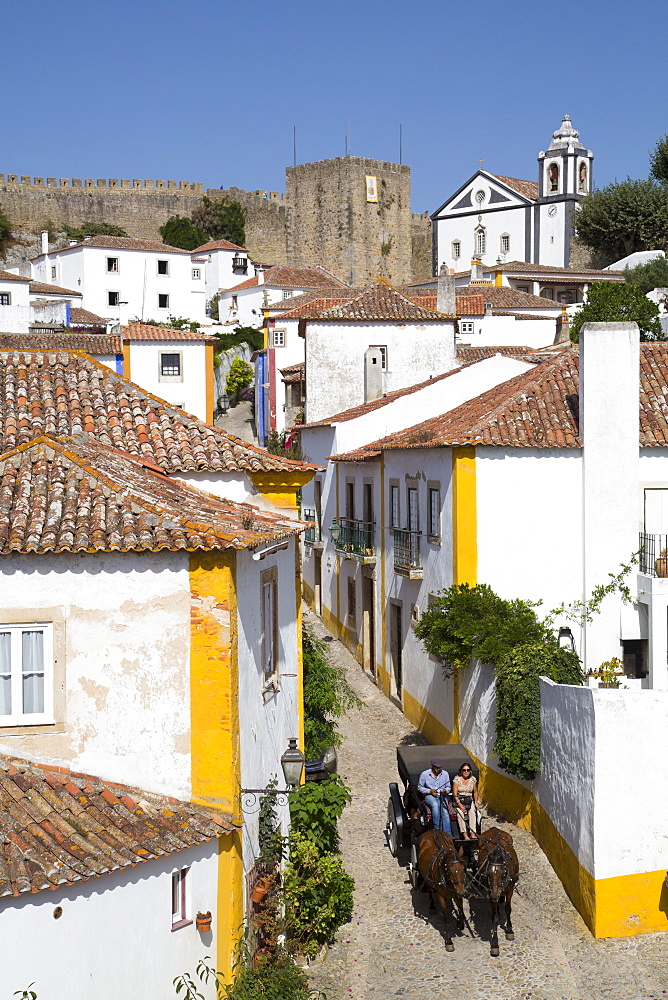 Horse drawn carriage, and overview of City with Medieval Castle in the background, Obidos, Portugal, Europe