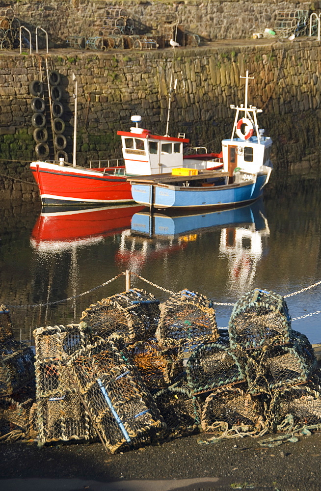 Lobster creels in the foreground with fishing boats in the harbour, Crail, Fife, Scotland, United Kingdom, europe