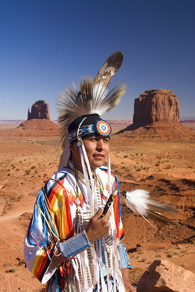 Navajo man in traditional costume, with Merrick Butte on the right and East Mitten Butte on the left in the background, Monument Valley Navajo Tribal Park, Utah, United States of America, North America