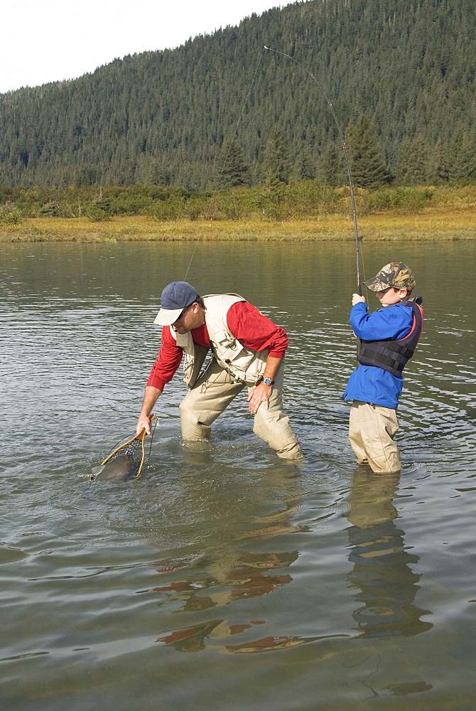 Boy catching a Silver (Coho) salmon (Oncorhynchus kisutch) with dad's help, Coghill Lake, Alaska, United States of America, North America