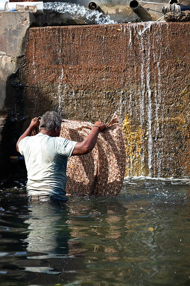 Man rinsing fabric of excess dye in factory well after block printing, before leaving in the sun to dry.