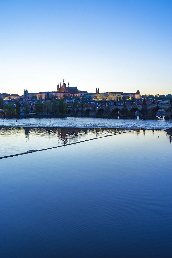 View of Charles Bridge, the Castle District and St. Vitus's Cathedral across the Vltava River at sunset, Prague, Czech Republic, Europe