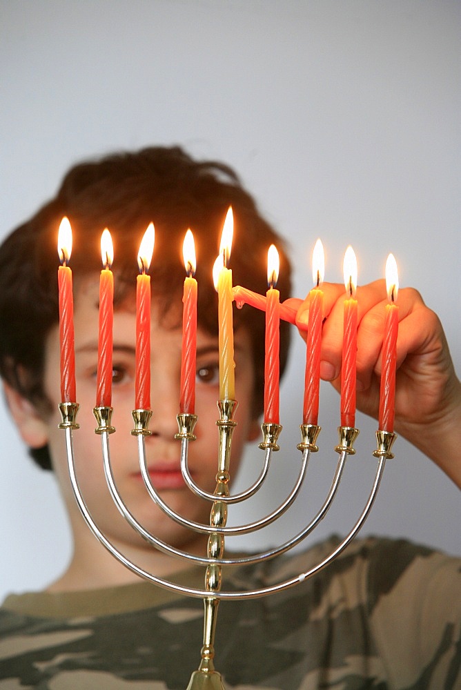 Boy lighting Hanukkah candles