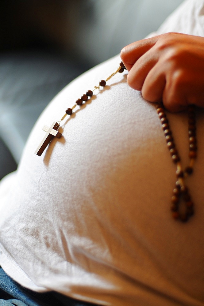 Pregnant woman with prayer beads, Paris, France, Europe