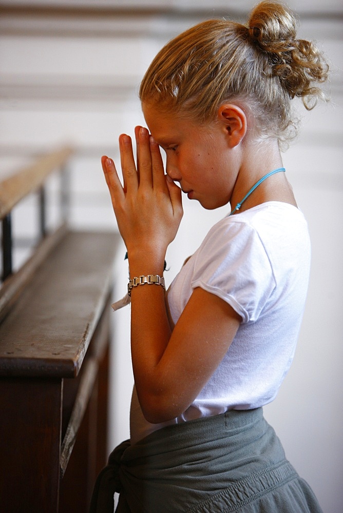 Girl praying in church, Saint Nicolas de Veroce, Haute Savoie, France, Europe