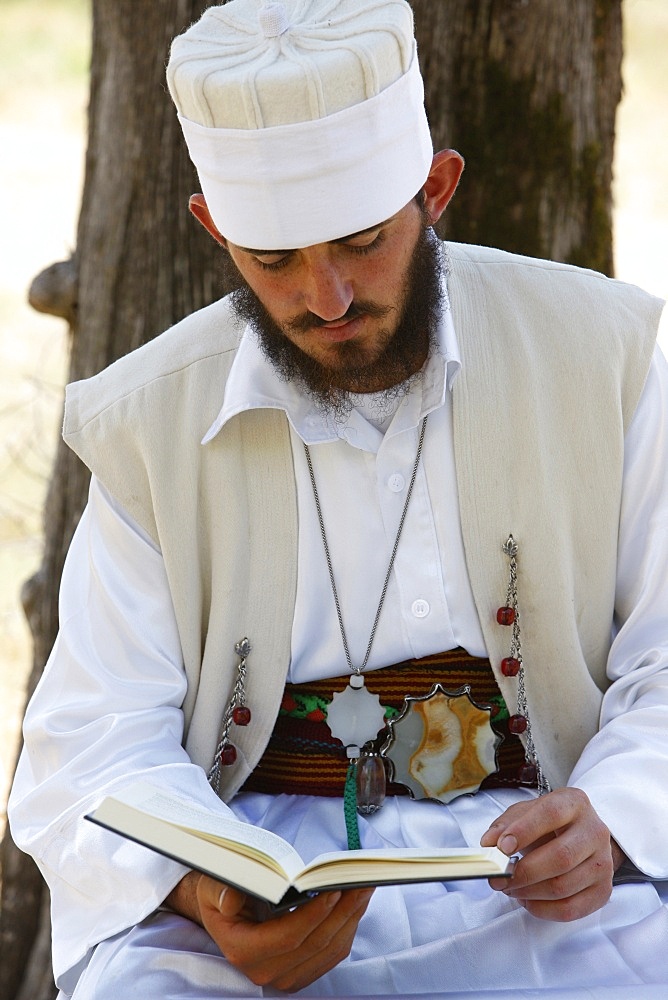 A 22-year old dervish, Myrteza Shehu, reading under a tree in Melani tekke, Vranishti, Girokastre, Albania, Europe