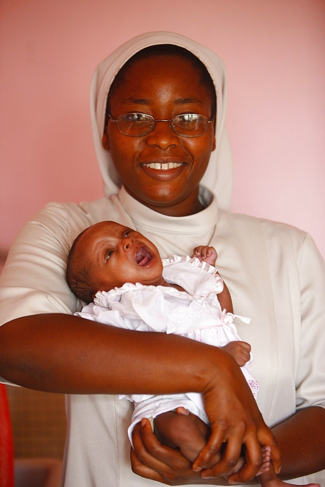 Franciscan sister holding an orphan at nursery and kindergarten run by Catholic nuns, Lome, Togo, West Africa, Africa