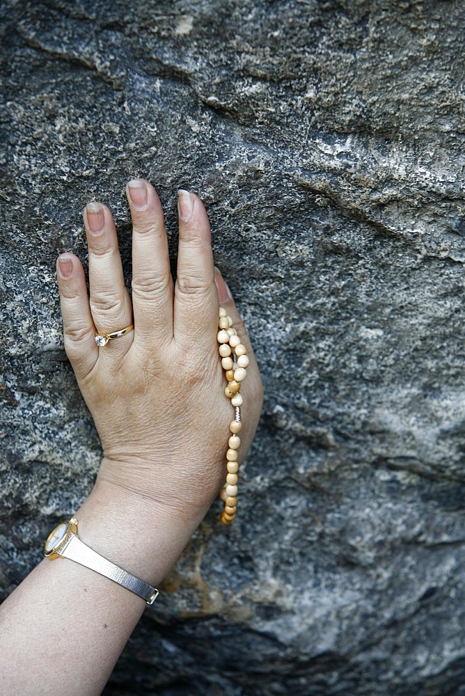 Pilgrim touching the Lourdes grotto, Lourdes, Hautes Pyrenees, France, Europe