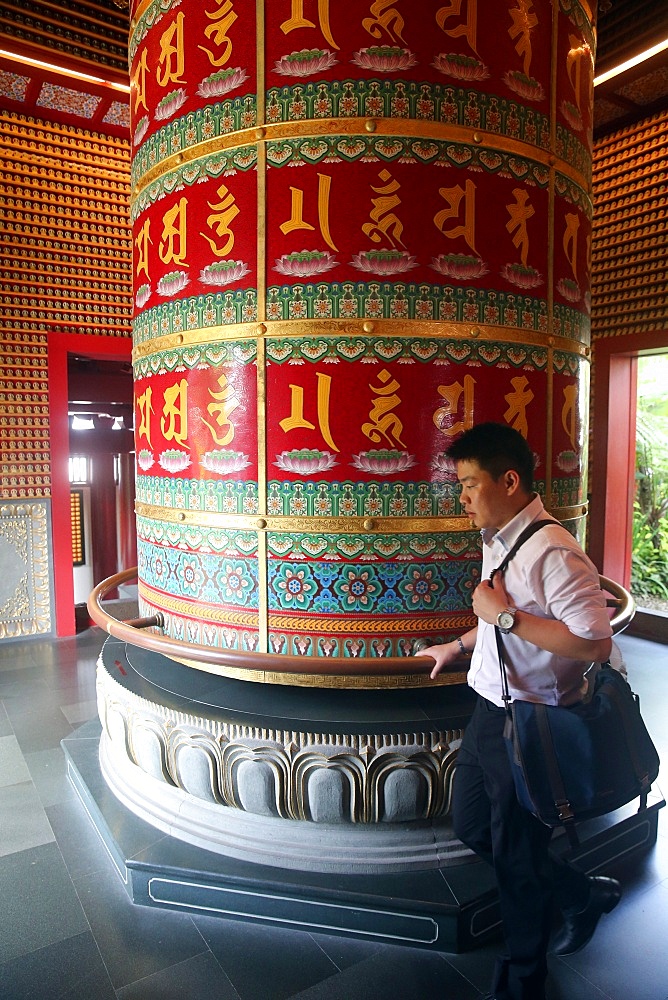 Worshipper and Viarocana Buddhist prayer wheel, Buddha Tooth Relic Temple in Chinatown, Singapore, Southeast Asia, Asia