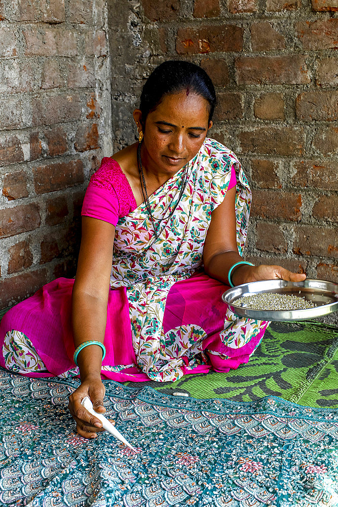 Adivasi woman sticking beads onto a sari in a village in Narmada district, Gujarat, India, Asia