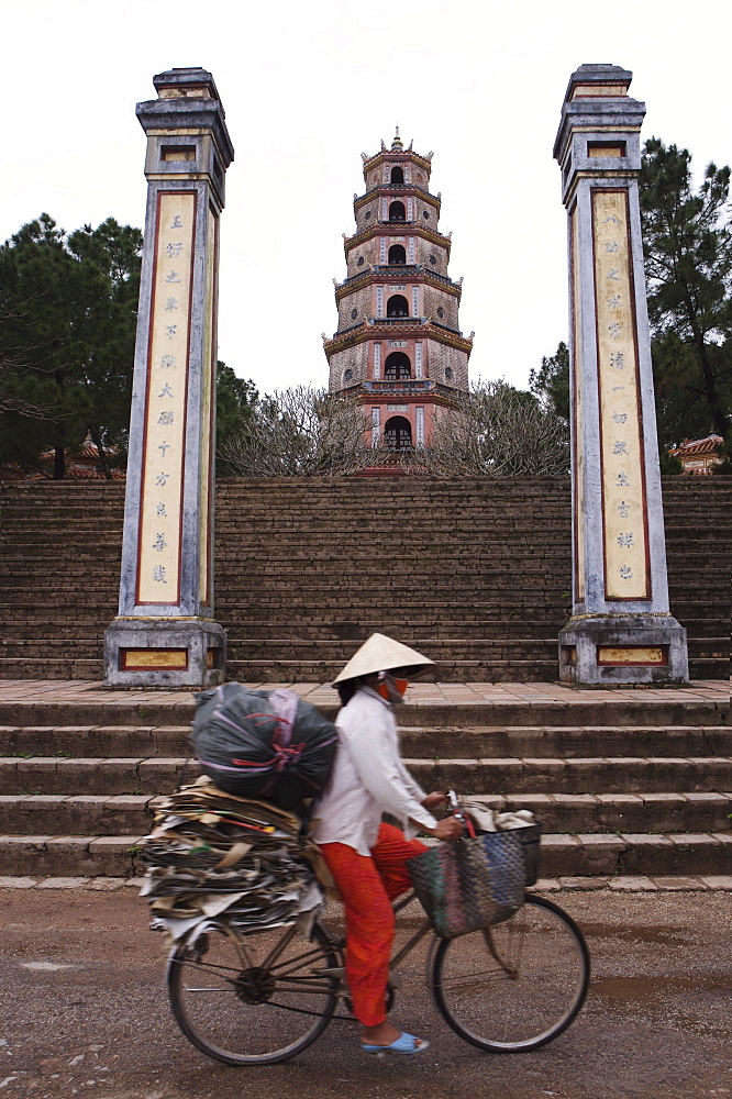 Woman on bicycle in front of Thien Mu Pagoda, Hue, Vietnam, Indochina, Southeast Asia, Asia