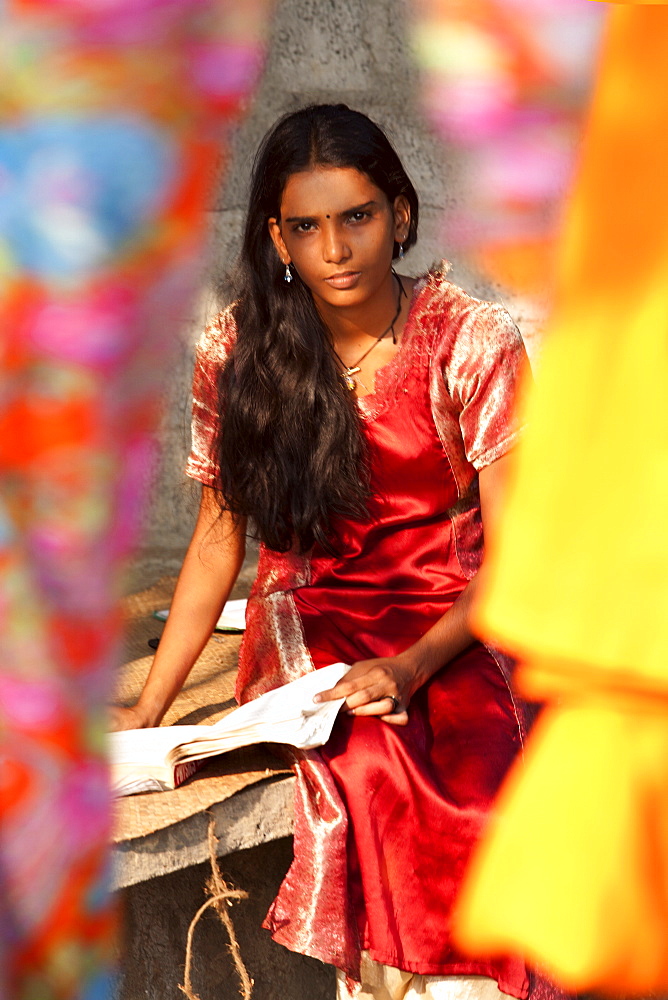 Student girl, sitting behind bright coloured silks, Kerala, India, Asia