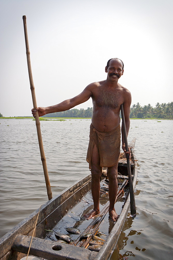 Fisherman standing in boat with fish, Kerala, India, Asia