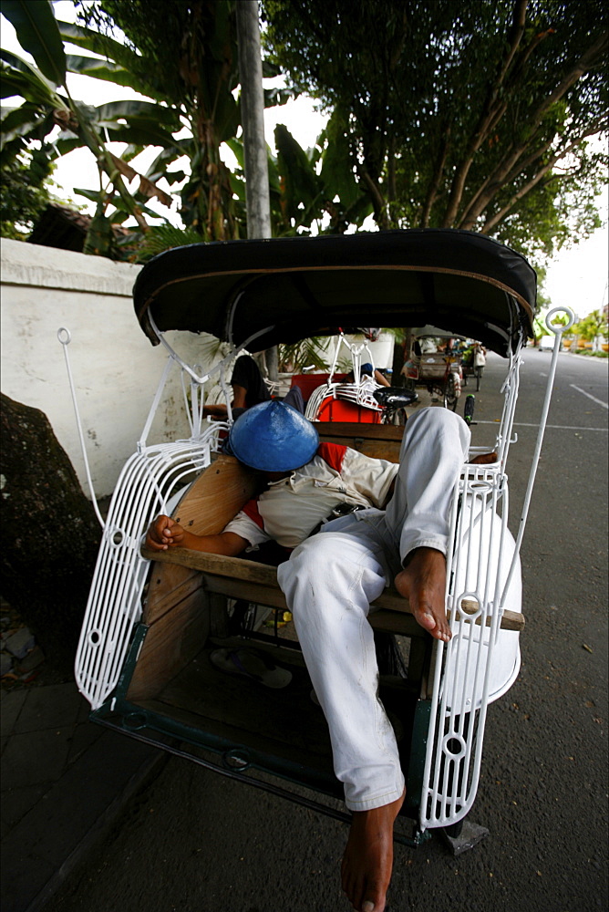 A tuk tuk driver sleeeping in front of the Prambanan temple, Java, Indonesia, Southeast Asia, Asia