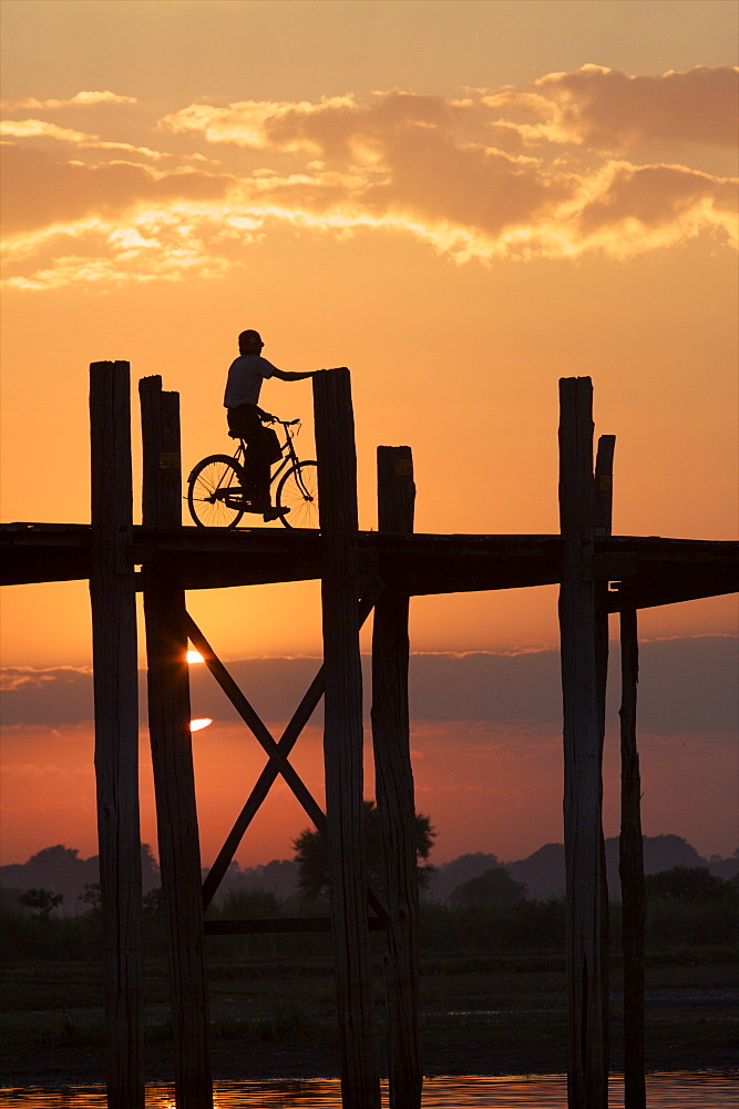 Cyclist on the U Bein teak bridge at sunset, Amarapura, Mandalay, Myanmar (Burma), Asia