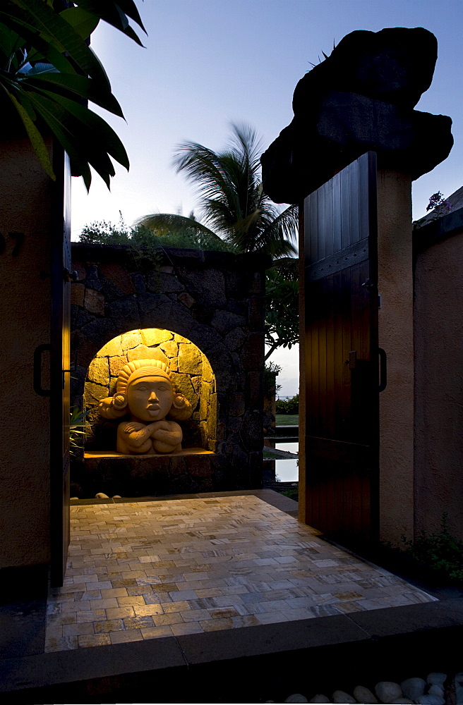 Illuminated sculptural head at dusk within a villa entrance, Baie aux Tortues, Pointe aux Pimentes, Mauritius, Africa