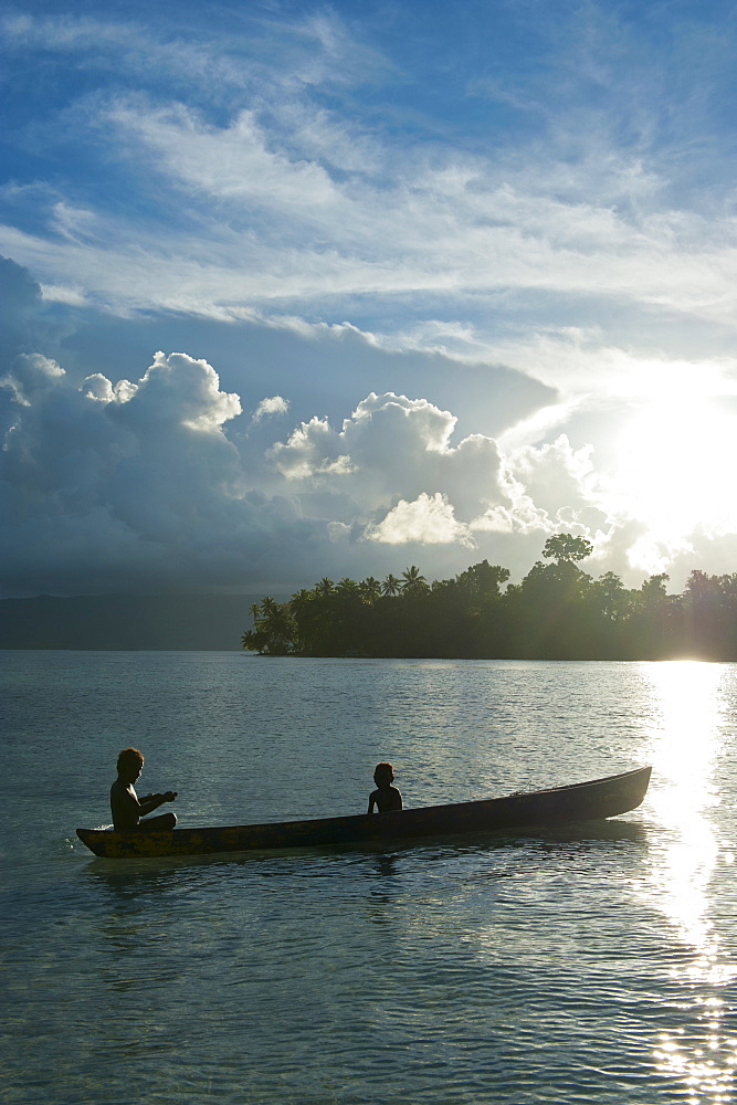 Boys in a canoe in backlit in the Marovo Lagoon, Solomon Islands, Pacific