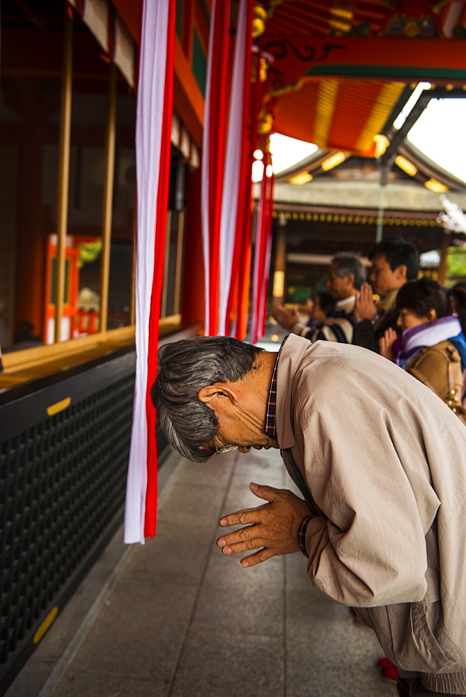 Praying pilgrim in the Endless Red Gates of Kyoto's Fushimi Inari Shrine, Kyoto, Japan, Asia