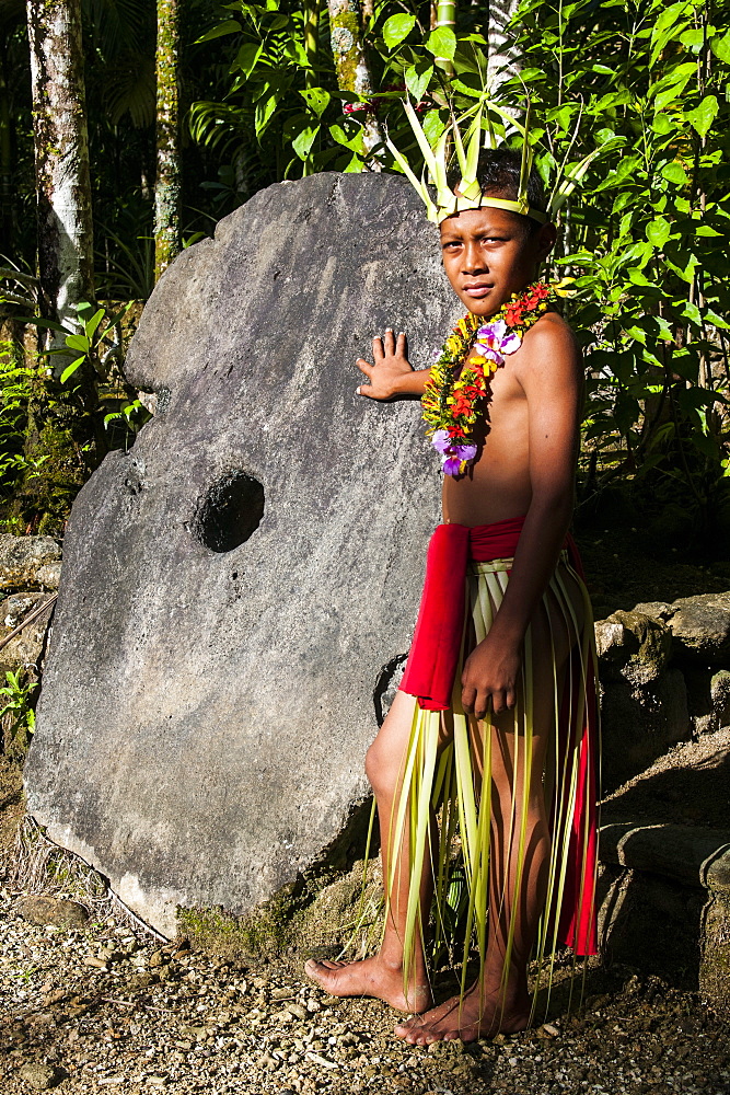 Young boy in traditional dress on the island of Yap standing before a huge stone money, Federated States of Micronesia, Caroline Islands, Pacific