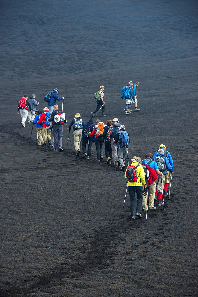 Tourists walking in a line through the lava sands of the Tolbachik volcano, Kamchatka, Russia, Eurasia