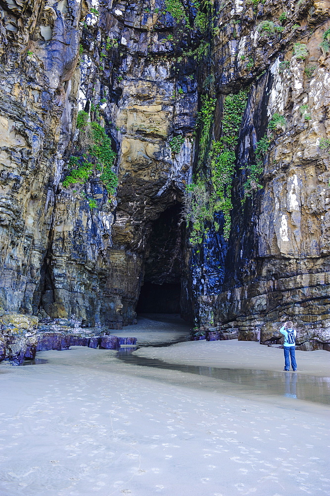 Woman looking at the giant entrance of the Cathedral caves, The Catlins, South Island, New Zealand, Pacific