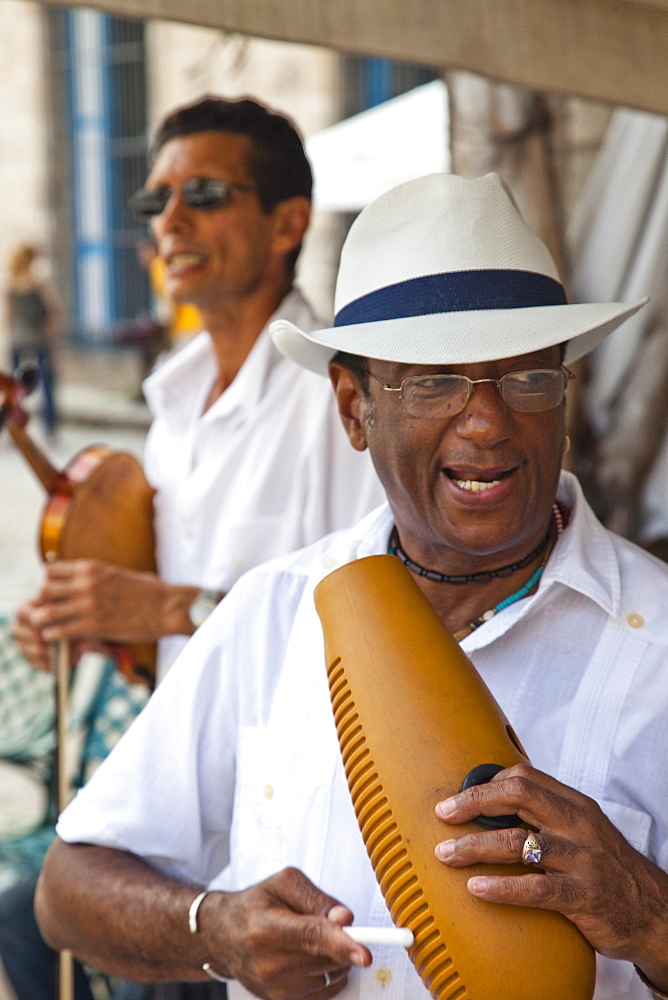 Men playing music on a guiro, a percussive instrument essential in salsa music, and a violin, in Plaza de la Catedral, Havana, Cuba, West Indies, Central America