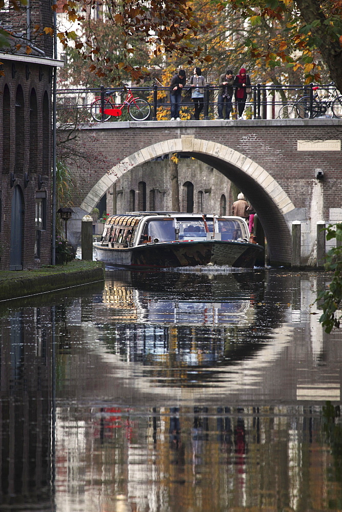 A sightseeing barge under a bridge on the Oudegracht Canal in the Dutch city of Utrecht, Utrecht Province, Netherlands, Europe