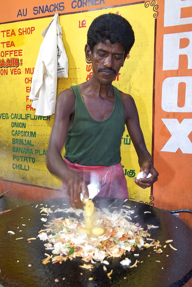 Man cooking South Indian style scrambled eggs at a roadside dhaba in Pondicherry India