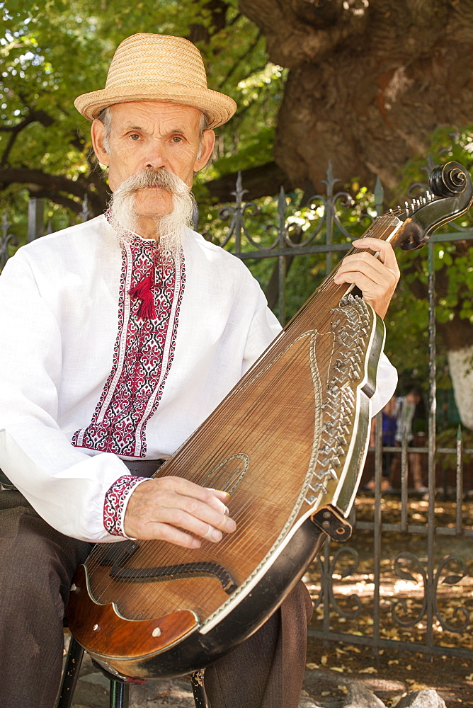 An elderly Ukrainian bandurist playing a bandura in a park in Kiev, Ukraine, Europe