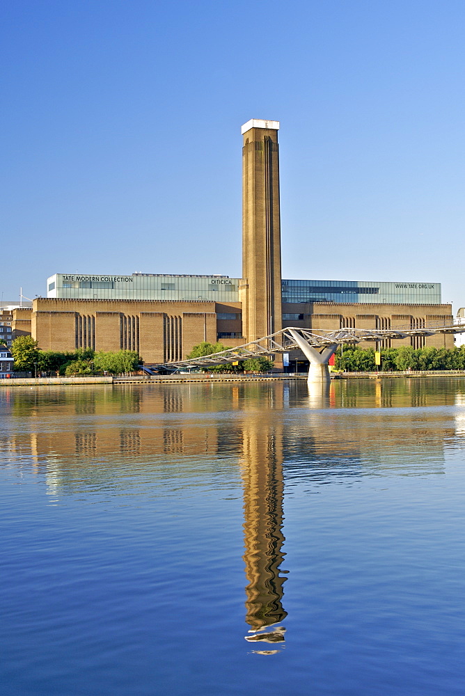 Early morning view of the Tate Modern art Gallery and Millenium Bridge reflecting in the Thames River in London. The Tate Modern is the converted former Bankside power station on the south bank of the Thames River. It was built in two phases between 1947 and 1963 and was designed by Sir Giles Gilbert Scott.