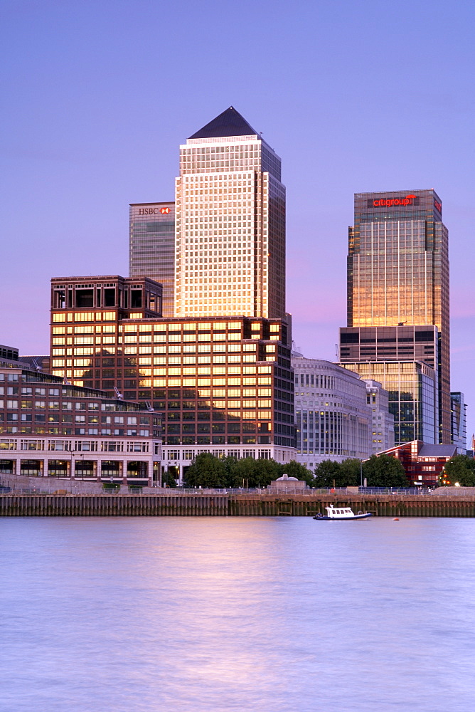 Dusk view across the Thames River of Canary Wharf Tower and other buildings in the docklands on the Isle of Dogs in London. Canary Wharf Tower is the tallest building in Britain and the architect was Cesar Pelli.