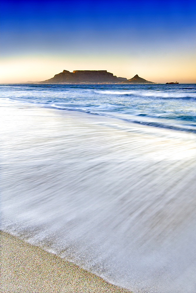 A view of Table Mountain and the city of Cape Town seen across Table bay from Bloubergstrand at dawn.